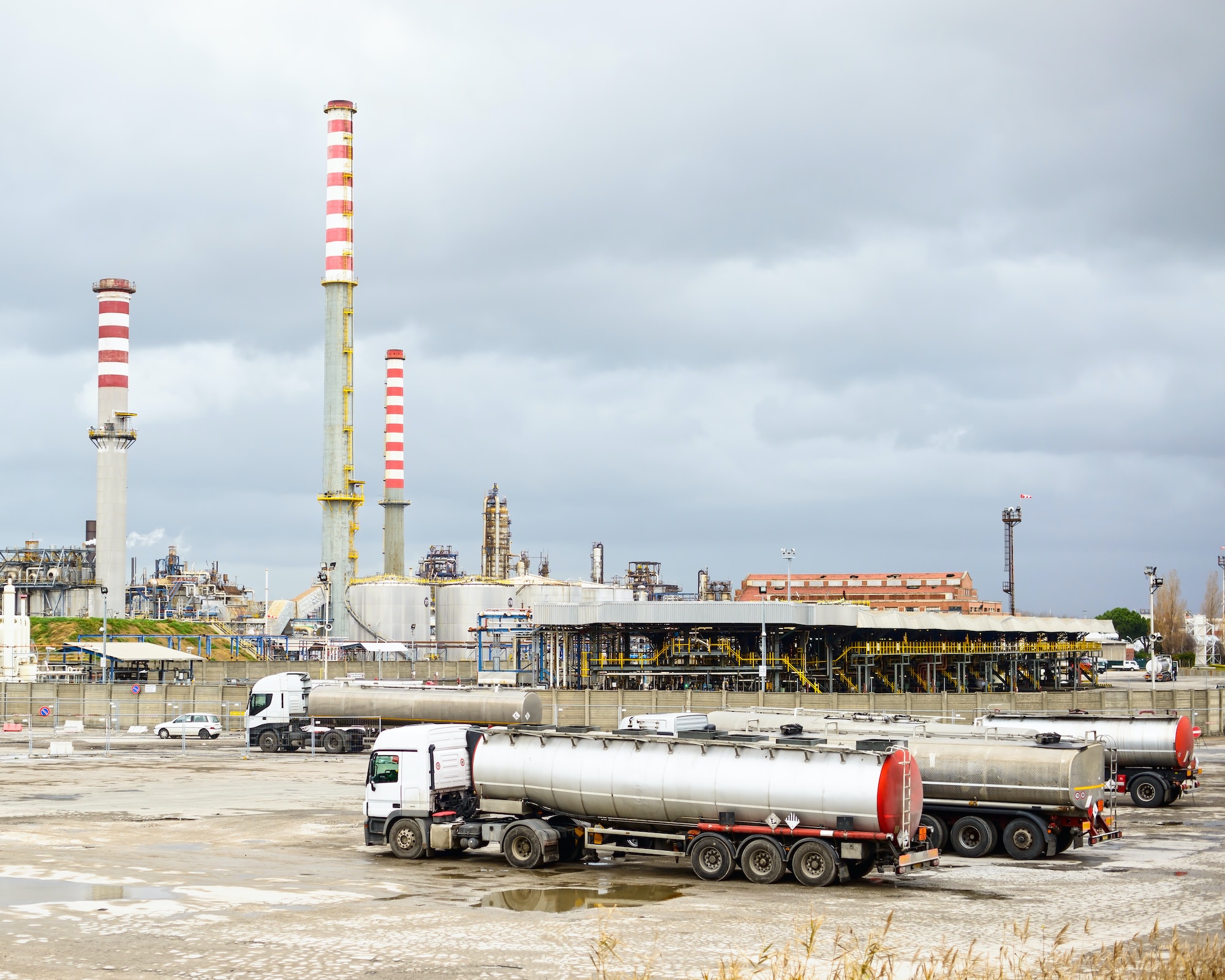 BettyJet Diesel Truck – Muddy Job Site Delivery Florida Oil refinery with smoke stacks and tanker trucks in a fuel delivery setting, highlighting industrial infrastructure and logistics for fuel services.